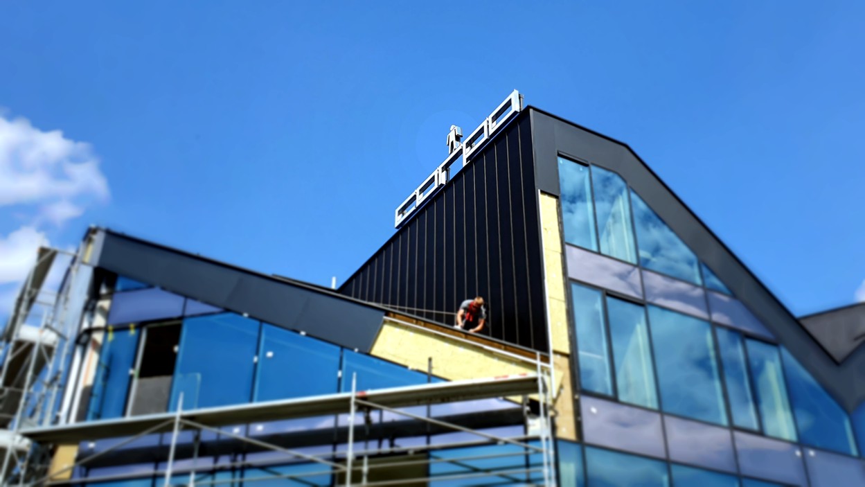 Logo ze święcącym licem zamontowane na konstrukcji stalowej na dachu budynku